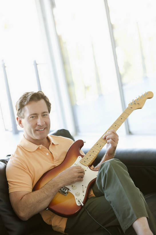 西方人,一个人,客厅,坐,笑,微笑,露齿笑,竖图,室内,白天,正面,窗户,沙发,欧洲,欧洲人,仅一个男性,仅一个人,仅一个中年男性,握,阴影,服装,裤子,朦胧,模糊,反射,影子,电吉他,乐器,弦乐器,弹奏,二郎腿,拿,拿着,注视,牛仔裤,休闲装,玻璃窗,衣服,观察,看,休闲,休闲服,握着,服饰,观看,察看,起居室,关注,弹拨弦鸣乐器,客堂,男人,男性,中年男性,白种人,坐着,半身,彩图,弹拨弦乐器,皮沙发