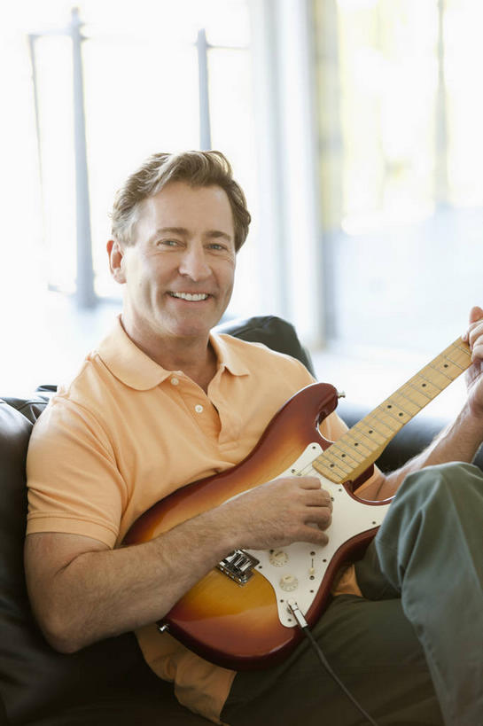 西方人,一个人,客厅,坐,笑,微笑,露齿笑,竖图,室内,白天,正面,窗户,沙发,欧洲,欧洲人,仅一个男性,仅一个人,仅一个中年男性,握,阴影,服装,裤子,朦胧,模糊,反射,影子,电吉他,乐器,弦乐器,弹奏,二郎腿,拿,拿着,注视,牛仔裤,休闲装,玻璃窗,衣服,观察,看,休闲,休闲服,握着,服饰,观看,察看,起居室,关注,弹拨弦鸣乐器,客堂,男人,男性,中年男性,白种人,坐着,半身,彩图,弹拨弦乐器,皮沙发