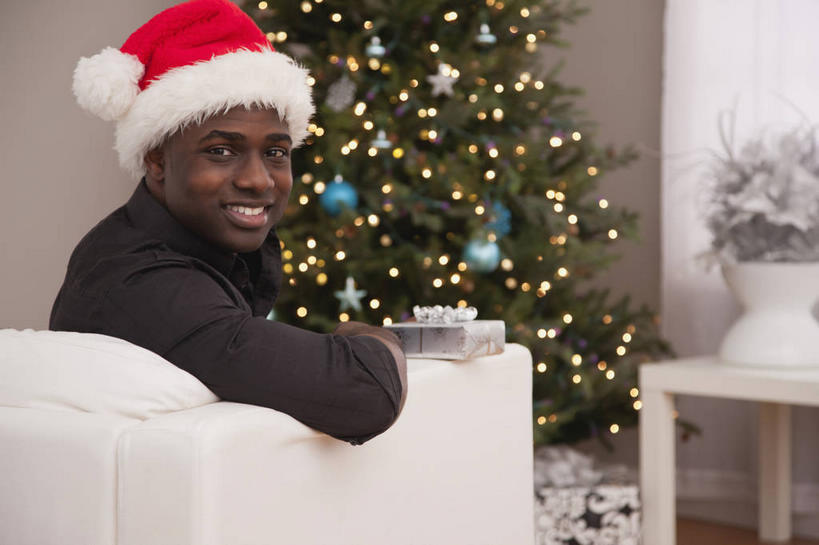 西方人,一个人,客厅,坐,笑,微笑,露齿笑,横图,室内,白天,侧面,植物,沙发,花瓶,帽子,照明,欧洲,非洲,圣诞节,黑人,欧洲人,仅一个男性,仅一个人,阴影,服装,节日,庆祝,装饰,盛开,光线,彩灯,挂饰,影子,灯光,圣诞树,圣诞球,花蕾,扭头,注视,休闲装,文化,玻璃制品,灯,球,花,花瓣,花朵,鲜花,树,树木,仅一个年轻男性,衣服,红色,绿色,自然,玻璃瓶,瓶子,灯具,花苞,花蕊,观察,看,转头,庆典,休闲,球体,休闲服,圣诞帽,服饰,花灯,生长,成长,观看,纪念,华丽,修饰,照亮,点缀,察看,起居室,照明设备,关注,布艺沙发,圣诞灯,衬托,美观,雅致,雅观,棉帽,客堂,男人,男性,年轻男性,非洲人,坐着,半身,彩图