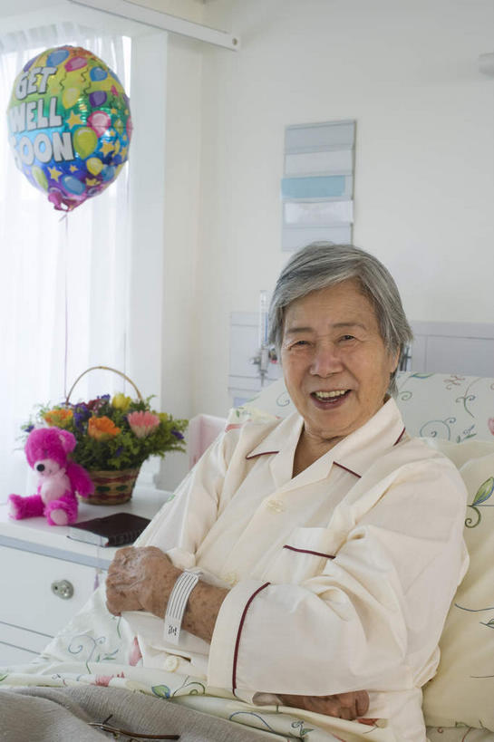 东方人,一个人,坐,笑,双手交叉,微笑,露齿笑,竖图,室内,白天,侧面,窗户,窗帘,床,亚洲,仅一个女性,仅一个人,装饰,花篮,塑料,墙,床单,注视,黄种人,被子,玻璃窗,墙壁,墙面,气球,塑料制品,床头柜,观察,看,靠,靠着,橡胶,单人床,仅一个老年女性,观看,华丽,修饰,点缀,察看,双手抱胸,被单,关注,橡胶制品,病号服,衬托,美观,雅致,雅观,老年女性,女人,女性,亚洲人,坐着,半身,彩图