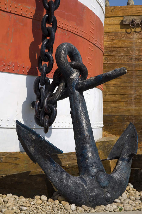 无人,竖图,室外,白天,正面,石头,金属制品,许多,阴影,光线,金属,石子,影子,墙,很多,墙壁,墙面,一个,红色,白色,阳光,单个,锚,铁环,锁链,链条,束缚,限制,约束,船锚,石块,岩石,彩图