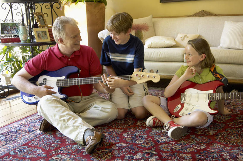 西方人,儿童,中年人,三个人,家庭,父亲,女儿,儿子,坐,跪,笑,盘腿,微笑,露齿笑,横图,室内,白天,正面,纯洁,地毯,柜子,沙发,欧洲,欧洲人,握,装饰,编织,手工艺品,吉他,乐器,弦乐器,织物,弹奏,拿,拿着,注视,小孩,工艺品,橱柜,观察,看,温暖,温馨,父女,父子,一家人,父爱,可爱,童年,童趣,握着,观看,华丽,修饰,点缀,和睦,察看,关注,弹拨弦鸣乐器,童真,烂漫,无邪,衬托,美观,雅致,雅观,天真,男孩,男人,男性,女孩,女人,女性,中年男性,白种人,孩子,跪着,盘腿而坐,盘膝,盘着腿的,盘着腿坐,双腿交叉,坐着,彩图,全身,融洽,弹拨弦乐器,男生,女生,皮沙发