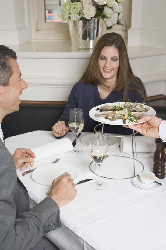 海鲜,红酒,葡萄酒,西方人,中年人,三个人,家庭,夫妻,服务员,餐厅,站,坐,捧,笑,微笑,露齿笑,竖图,室内,白天,正面,爱情,餐桌,桌子,杯子,餐具,欧洲,欧洲人,服装,朦胧,模糊,布料,碟子,高脚杯,盘,红酒杯,牡蛎,白葡萄酒,酒类,浪漫,布纹,注视,休闲装,水产,顾客,海洋生物,玻璃制品,酒,桌布,饮料,衣服,盘子,餐巾,酒杯,碟,台布,观察,看,站着,休闲,温暖,温馨,一家人,休闲服,恩爱,恋人,服饰,餐台,观看,生蚝,和睦,察看,葡萄酒杯,关注,水生动物,海产品,水生物,海底动物,主顾,男人,男性,女人,女性,中年男性,中年女性,白种人,夫妇,情侣,服务生,侍者,玻璃杯,端,端着,捧着,手捧,站立,坐着,半身,彩图,餐馆,饭店,饭馆,伴侣,融洽