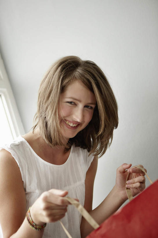 西方人,一个人,站,笑,微笑,露齿笑,竖图,室内,白天,正面,购物,消费,窗户,落地窗,袋子,欧洲,欧洲人,仅一个年轻女性,仅一个女性,仅一个人,握,服装,包装袋,手提袋,墙,购物袋,拿,拿着,扭头,注视,休闲装,玻璃窗,墙壁,墙面,一个,衣服,红色,白色,观察,看,站着,转头,休闲,休闲服,握着,金融,服饰,单个,观看,察看,购买,关注,贸易,年轻女性,女人,女性,白种人,站立,半身,彩图