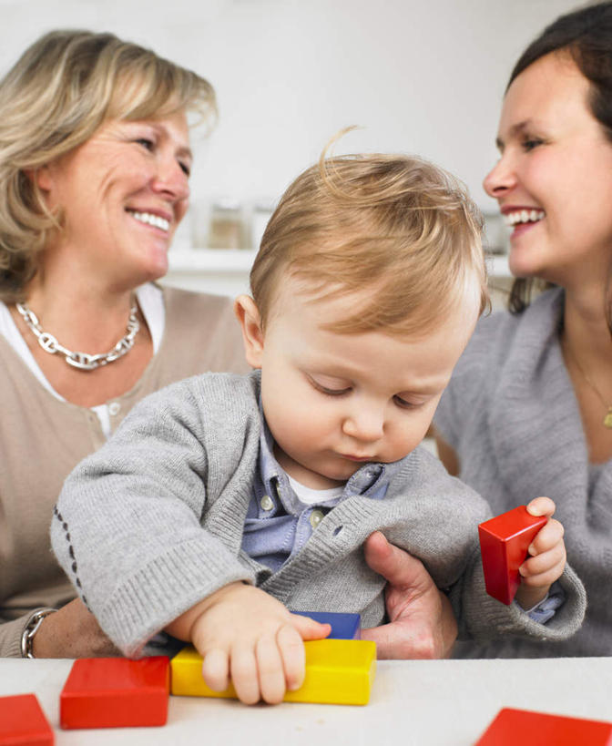 西方人,婴儿,儿童,老年人,三个人,母亲,儿子,祖母,三代同堂,坐,笑,微笑,露齿笑,竖图,室内,白天,正面,游戏,纯洁,桌面,桌子,玩具,项链,欧洲,欧洲人,握,服装,木制,墙,拿,玩,拿着,扭头,注视,休闲装,娱乐,祖孙三代,相视,墙壁,墙面,装饰品,小孩,衣服,木制品,饰品,首饰,低头,观察,看,转头,休闲,温暖,温馨,母子,面对面,休闲服,可爱,母爱,童年,童趣,益智,握着,服饰,奶奶,观看,活动,祖孙,对视,和睦,察看,互视,发泄,关注,消遣,智力,宝宝,相对,童真,烂漫,无邪,外婆,外祖母,相看,外孙子,宣泄,垂头,天真,老年女性,年轻女性,女人,女性,白种人,孩子,年轻人,全家福,孙子,玩耍,嬉戏,坐着,半身,彩图,融洽,多代同堂,妈妈