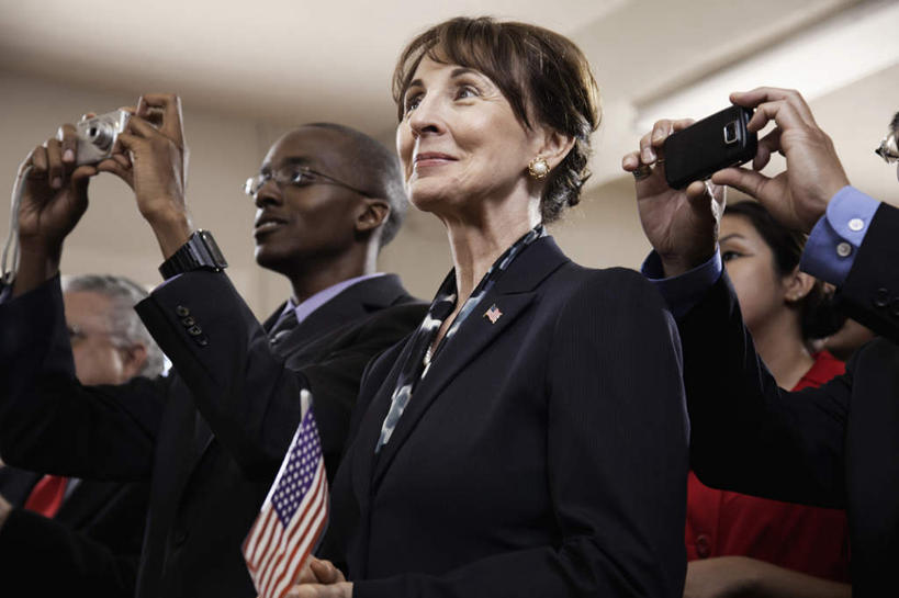 冲浪,西方人,商务人士,商务女性,站,举,笑,微笑,室内,白天,侧面,旗帜,国旗,相机,欧洲,非洲,黑人,欧洲人,阴影,套装,朦胧,模糊,光线,眼镜,影子,墙,灯光,许多人,注视,星条旗,墙壁,墙面,拍照,数码相机,观察,看,托,站着,一群人,美国国旗,摄影,观看,察看,徽章,关注,商务装,近视眼镜,工薪阶层,老年女性,男人,男性,年轻男性,年轻女性,女人,女性,白种人,非洲人,白领,上班族,旗,照相机,举起,举手,举着,抬头,向上举,向上伸,向上托,仰头,站立,半身,彩图,照相,美利坚合众国国旗,公民