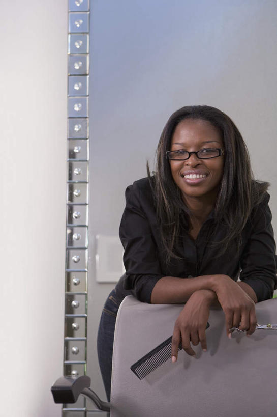 西方人,一个人,理发师,坐,笑,微笑,露齿笑,竖图,室内,白天,正面,镜子,欧洲,非洲,黑人,欧洲人,仅一个女性,仅一个人,一把,一副,握,阴影,服装,反射,眼镜,影子,墙,梳子,注视,休闲装,墙壁,墙面,衣服,日用品,观察,看,仅一个中年女性,休闲,休闲服,握着,服饰,观看,理发店,镜像,察看,镜面,关注,近视眼镜,美发用品,女人,女性,中年女性,非洲人,发型师,理发员,美发师,坐着,半身,彩图