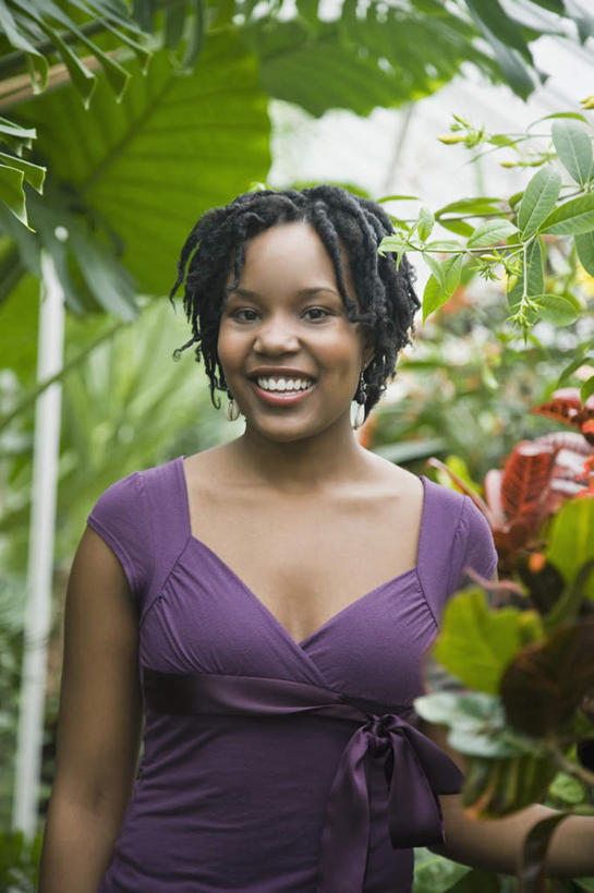 西方人,一个人,站,笑,微笑,露齿笑,竖图,室外,白天,正面,植物,叶子,欧洲,非洲,黑人,欧洲人,仅一个年轻女性,仅一个女性,仅一个人,阴影,服装,光线,影子,绿叶,注视,休闲装,树,树木,衣服,绿色,紫色,阳光,自然,观察,看,站着,休闲,休闲服,嫩叶,服饰,生长,成长,观看,察看,关注,年轻女性,女人,女性,非洲人,叶,叶片,站立,半身,彩图