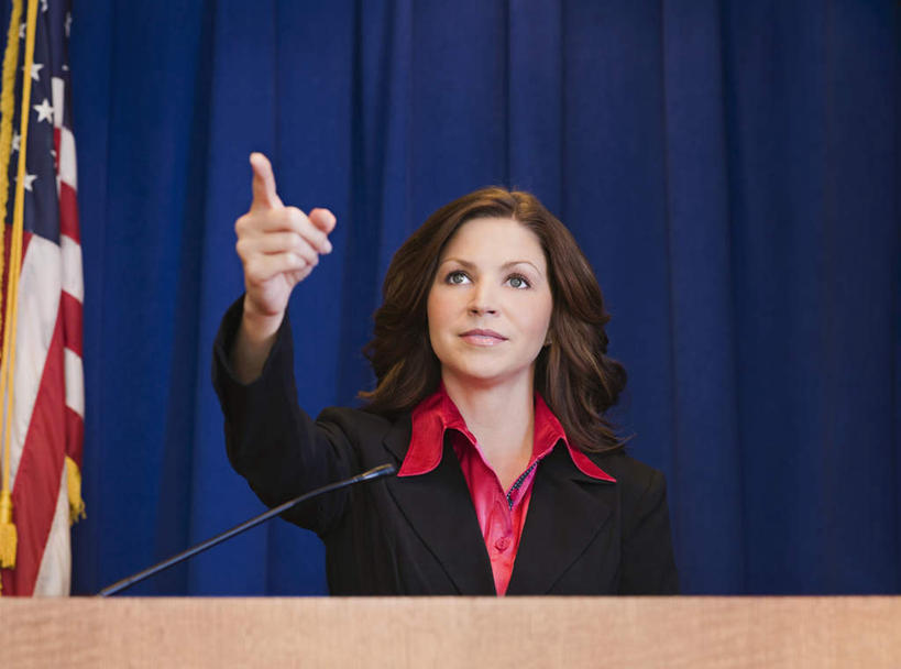 西方人,一个人,商务人士,商务女性,站,说,横图,室内,白天,正面,讨论,旗帜,国旗,欧洲,欧洲人,仅一个女性,仅一个人,指,阴影,套装,反射,影子,注视,指点,星条旗,蓝色,话筒,讲台,观察,看,站着,仅一个中年女性,美国国旗,帷幕,观看,察看,麦克风,指向,关注,扩音器,帷幔,演说台,商务装,幕布,幕帘,传声器,工薪阶层,演讲台,微音器,帷幔布,交流,女人,女性,中年女性,白种人,白领,上班族,旗,沟通,讲话,交谈,商讨,说话,谈话,站立,半身,彩图,美利坚合众国国旗