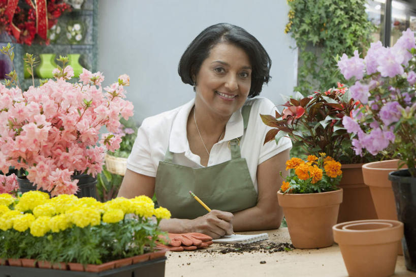 西方人,一个人,商务人士,商务女性,花店,商店,坐,笑,微笑,露齿笑,横图,室内,白天,正面,安全,植物,叶子,欧洲,非洲,黑人,欧洲人,仅一个女性,仅一个人,握,套装,服装,盛开,笔,盆栽,围裙,纹理,泥土,土壤,绿叶,办公用品,防护,记事本,盆景,拿,花蕾,拿着,注视,休闲装,商铺,文具,花,花瓣,花朵,鲜花,衣服,绿色,自然,本子,笔记本,铅笔,手套,学习用品,花苞,花蕊,观察,看,休闲,休闲服,嫩叶,握着,服饰,仅一个老年女性,生长,成长,观看,保护,文具用品,察看,关注,保险,商务装,工薪阶层,肌理,保全,周全,安稳,安定,防护手套,市肆,商号,平安,老年女性,女人,女性,非洲人,白领,上班族,叶,叶片,叶脉,坐着,半身,彩图,店铺