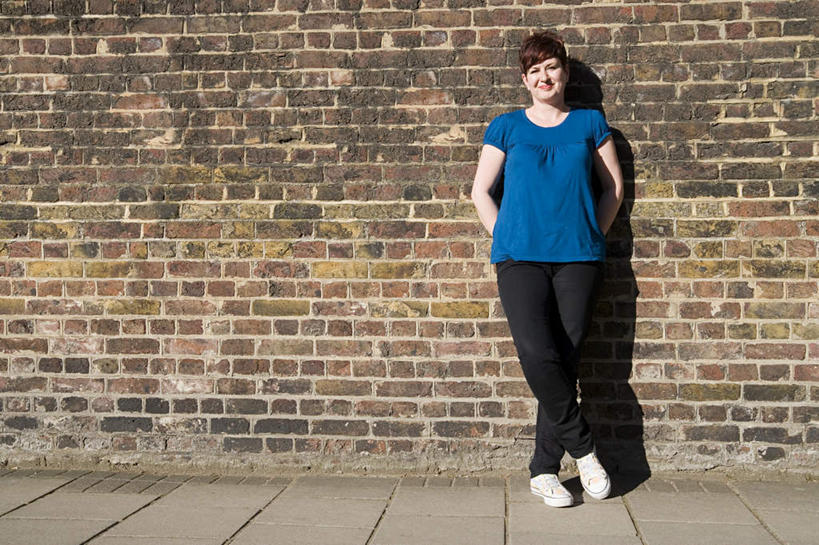 西方人,一个人,站,笑,微笑,横图,室外,白天,正面,运动鞋,鞋子,欧洲,欧洲人,仅一个女性,仅一个人,阴影,服装,裤子,反射,影子,墙,注视,牛仔裤,休闲装,墙壁,墙面,衣服,蓝色,观察,看,靠,靠着,站着,仅一个中年女性,休闲,休闲服,服饰,转身,观看,休闲鞋,察看,关注,背手,女人,女性,中年女性,白种人,站立,彩图,全身