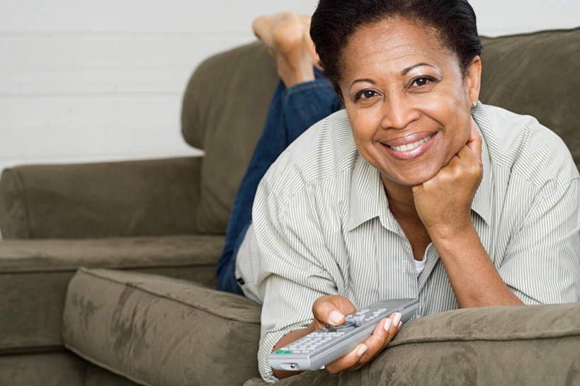 西方人,一个人,客厅,笑,微笑,露齿笑,横图,室内,白天,正面,靠垫,沙发,欧洲,非洲,黑人,欧洲人,仅一个女性,仅一个人,撑,握,服装,裤子,靠枕,拿,拿着,托腮,注视,牛仔裤,休闲装,衣服,抱枕,遥控器,枕头,观察,看,趴着,托,仅一个中年女性,休闲,休闲服,握着,服饰,观看,察看,起居室,关注,托下巴,布艺沙发,客堂,女人,女性,中年女性,非洲人,趴,半身,彩图