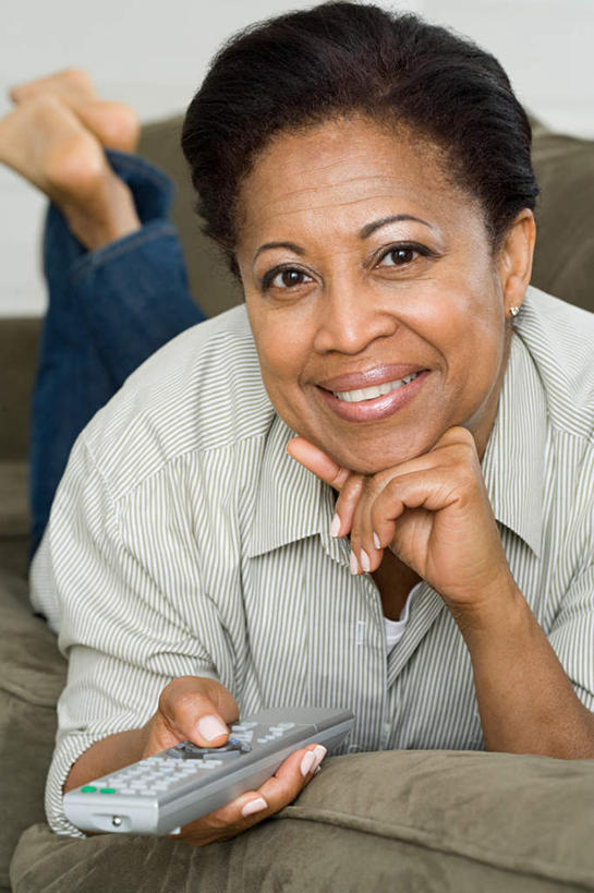 西方人,一个人,客厅,笑,微笑,露齿笑,竖图,室内,白天,正面,靠垫,沙发,欧洲,非洲,黑人,欧洲人,仅一个女性,仅一个人,撑,握,服装,裤子,靠枕,拿,拿着,托腮,注视,牛仔裤,休闲装,衣服,抱枕,遥控器,枕头,观察,看,趴着,托,仅一个中年女性,休闲,休闲服,握着,服饰,观看,察看,起居室,关注,托下巴,布艺沙发,客堂,女人,女性,中年女性,非洲人,趴,半身,彩图