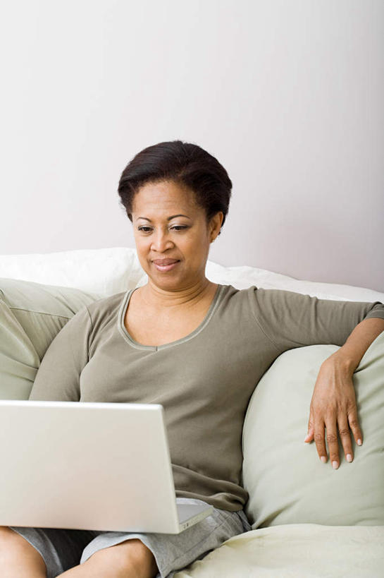 西方人,一个人,客厅,坐,笑,微笑,露齿笑,竖图,室内,白天,正面,电脑,笔记本电脑,靠垫,沙发,欧洲,非洲,黑人,欧洲人,仅一个女性,仅一个人,服装,网络,靠枕,注视,休闲装,通讯设备,衣服,抱枕,枕头,观察,看,仅一个中年女性,休闲,休闲服,服饰,观看,察看,无线,起居室,关注,通信设备,无线网络,布艺沙发,无线上网,便携式电脑,客堂,手提电脑,女人,女性,中年女性,非洲人,坐着,半身,彩图