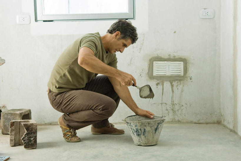 西方人,一个人,蹲,笑,微笑,露齿笑,横图,室内,白天,侧面,窗户,欧洲,欧洲人,仅一个男性,仅一个人,握,铲子,墙,拿,拿着,注视,水泥,开关,玻璃窗,墙壁,墙面,仅一个年轻男性,看,砖头,握着,操作,关注,装修工,男人,男性,年轻男性,白种人,蹲着,彩图,全身