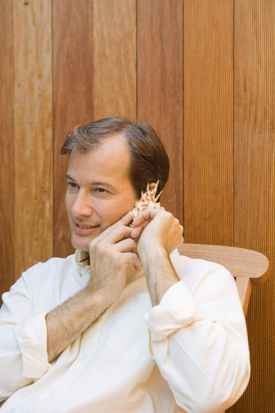 西方人,脸,头,脸颊,一个人,坐,笑,微笑,露齿笑,竖图,室内,白天,正面,衬衫,贝壳,椅子,欧洲,欧洲人,仅一个男性,仅一个人,仅一个中年男性,握,木椅,躺椅,拿,听,拿着,注视,白色,黑色,观察,看,握着,观看,察看,关注,男人,男性,中年男性,白种人,头部,脸部,脸蛋,面部,贝类外壳,海螺壳,软体动物外壳,坐着,半身,彩图,衬衣,短发