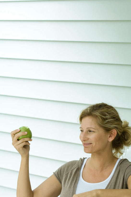 西方人,头发,一个人,站,笑,微笑,露齿笑,竖图,室外,特写,白天,侧面,苹果,水果,欧洲,欧洲人,仅一个女性,仅一个人,握,新鲜,墙,生食,食品,果实,拿,拿着,注视,休闲装,墙壁,墙面,食物,一个,黄色,看,倚靠,站着,仅一个中年女性,休闲,休闲服,握着,有机食品,绿色食品,单个,女人,女性,中年女性,白种人,站立,半身,彩图