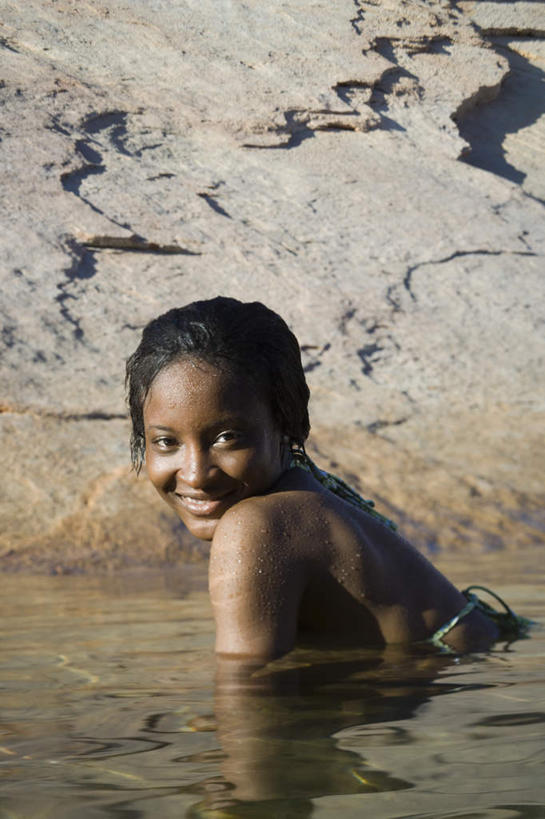 西方人,脸,头,脸颊,一个人,站,笑,微笑,露齿笑,竖图,室外,白天,侧面,湖,湖泊,石头,水,欧洲,非洲,黑人,欧洲人,仅一个年轻女性,仅一个女性,仅一个人,石子,湖面,水流,水面,扭头,注视,肩膀,湖水,观察,看,站着,转头,观看,察看,关注,沉积岩,水成岩,年轻女性,女人,女性,非洲人,头部,脸部,脸蛋,面部,石块,岩石,站立,半身,彩图