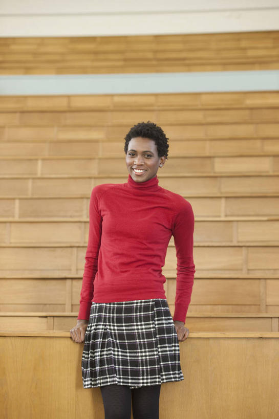 西方人,一个人,学校,教学楼,站,笑,微笑,露齿笑,竖图,室内,白天,正面,毛衣,桌子,欧洲,非洲,黑人,欧洲人,仅一个年轻女性,仅一个女性,仅一个人,木制,墙,注视,书桌,校园,墙壁,墙面,红色,课桌,木制品,观察,看,站着,教室,观看,察看,关注,线衫,毛线衣,绒线衣,年轻女性,女人,女性,非洲人,站立,半身,彩图,绒衣,套衫,套头毛衣,线衣,教学大楼,报告厅