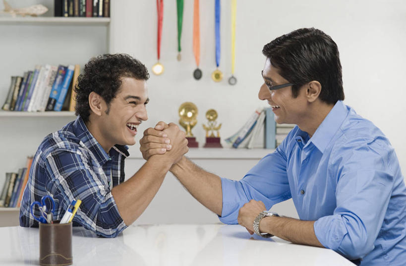 两个人,家庭,父亲,儿子,坐,笑,微笑,大笑,露齿笑,横图,室内,白天,侧面,游戏,兴奋,成功,胜利,比赛,桌面,桌子,书籍,笔筒,亚洲,五个,许多,修剪,阴影,服装,朦胧,模糊,时间,反射,工具,剪刀,时钟,手表,眼镜,影子,墙,大理石,玩,计时,注视,休闲装,右手,娱乐,相视,墙壁,墙面,两个,衣服,白色,容器,书柜,钟表,观察,看,张嘴,休闲,温暖,温馨,父子,一家人,面对面,休闲服,表,器皿,书橱,父爱,光彩,力量,扳手腕,服饰,观看,活动,储藏,对视,裁剪,腕表,和睦,察看,剪子,剪裁,切割,掰手腕,互视,储存,发泄,关注,消遣,智力,奖牌,相对,荣誉,奖品,近视眼镜,张大嘴巴,相看,哈哈大笑,宣泄,荣耀,大理石制品,比力,较劲,扳手劲,手肘,插笔器具,文房用具,光荣,较量,男人,男性,年轻男性,中年男性,亚洲人,印度人,胳膊,手臂,书,图书,钟,张开嘴,玩耍,嬉戏,坐着,半身,彩图,高兴,狂笑,融洽,贮存,奖杯