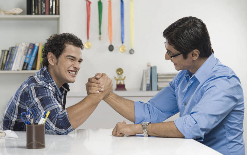 两个人,家庭,父亲,儿子,坐,笑,微笑,大笑,露齿笑,横图,室内,白天,侧面,游戏,兴奋,成功,胜利,比赛,桌面,桌子,书籍,笔筒,亚洲,五个,许多,修剪,阴影,服装,朦胧,模糊,时间,反射,工具,剪刀,时钟,手表,眼镜,影子,墙,大理石,玩,计时,注视,休闲装,右手,娱乐,相视,墙壁,墙面,两个,衣服,白色,容器,书柜,钟表,观察,看,张嘴,休闲,温暖,温馨,父子,一家人,面对面,休闲服,表,器皿,书橱,父爱,光彩,力量,扳手腕,服饰,观看,活动,储藏,对视,裁剪,腕表,和睦,察看,剪子,剪裁,切割,掰手腕,互视,储存,发泄,关注,消遣,智力,奖牌,相对,荣誉,奖品,近视眼镜,张大嘴巴,相看,哈哈大笑,宣泄,荣耀,大理石制品,比力,较劲,扳手劲,手肘,插笔器具,文房用具,光荣,较量,男人,男性,年轻男性,中年男性,亚洲人,印度人,胳膊,手臂,书,图书,钟,张开嘴,玩耍,嬉戏,坐着,半身,彩图,高兴,狂笑,融洽,贮存,奖杯