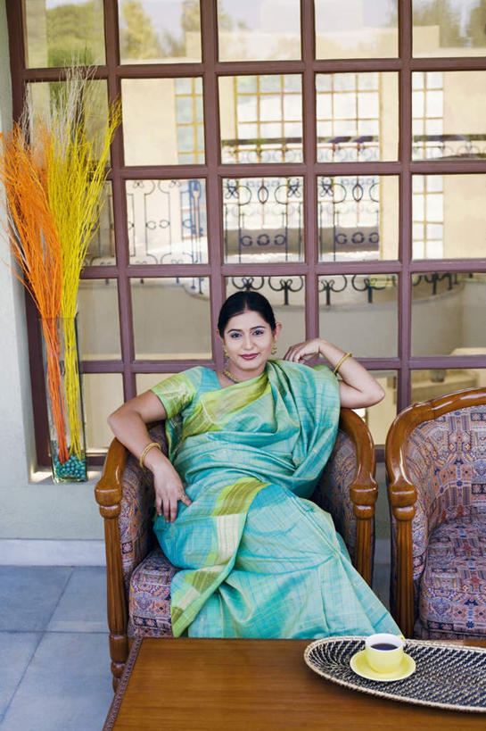 一个人,坐,笑,微笑,露齿笑,竖图,室内,白天,正面,民族服装,植物,窗户,落地窗,杯子,亚洲,仅一个年轻女性,仅一个女性,仅一个人,瓷器,盆栽,咖啡杯,盆景,陶瓷制品,二郎腿,注视,玻璃窗,绿色,自然,观察,看,服饰,生长,成长,观看,飘逸,察看,庄重,关注,瓷杯,追求,跷,纱丽,雅致,纱丽服,清婉,妍丽,年轻女性,女人,女性,亚洲人,印度人,坐着,半身,彩图,传统服装,民俗服,奢华