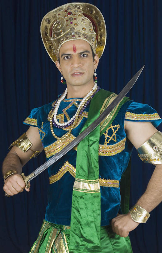 一个人,站,竖图,室内,白天,正面,民族服装,竞争,植物,帽子,项链,亚洲,仅一个男性,仅一个人,对抗,握,蓝色背景,冲突,草药,药草,刀具,拿,拿着,注视,破坏,中药,装饰品,仅一个年轻男性,饰品,首饰,刀,观察,看,站着,武器,战争,握着,摄影,影棚,观看,合金,损坏,豆蔻,察看,攻击,威胁,对立,关注,矛盾,兵器,药材,中草药,防御,中药材,本草,敌对,挫败,斗争,抗拒,抗衡,凶器,杀伤,威慑,消食,白豆蔻,危险,男人,男性,年轻男性,亚洲人,印度人,站立,半身,彩图,影棚拍摄,传统服装,民俗服,拍摄,匕首,开胃