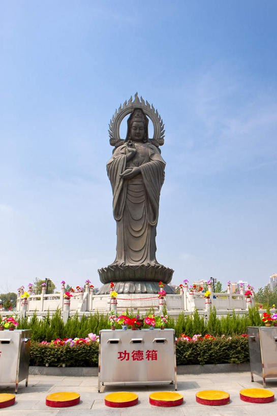 一个人,无人,寺庙,站,竖图,室外,白天,正面,民族服装,旅游,度假,智慧,名胜古迹,标志建筑,地标,建筑,雕塑,武汉,中国,亚洲,仅一个年轻女性,仅一个女性,仅一个人,阴影,服装,节日,神话,遗迹,艺术,装饰,盛开,光线,英文,标志,雕刻,雕像,文字,影子,字符,字母,花蕾,古迹,文化,文物,娱乐,标识,建设,古建筑,花,花瓣,花朵,鲜花,衣服,蓝色,蓝天,天空,阳光,工艺品,庙宇,天,花苞,花蕊,祈祷,站着,享受,休闲,健康,旅游胜地,放松,许愿,宗教,观音,服饰,佛教,信仰,晴朗,纪念,英文字母,祈求,美术,衣着,穿着,主题,传说,陈列,古文明,东亚,菩萨,湖北,湖北省,武汉市,万里无云,观音菩萨,归元寺,汉阳,中华人民共和国,省会,功能,美学,华中地区,鄂,衣饰,释教,慈悲,中国神话,观世音,观世音菩萨,观音大士,观自在菩萨,平安,年轻女性,女人,女性,晴空,晴空万里,站立,彩图,全身,传统服装,民俗服,庙,寺,归元禅寺,汉阳区