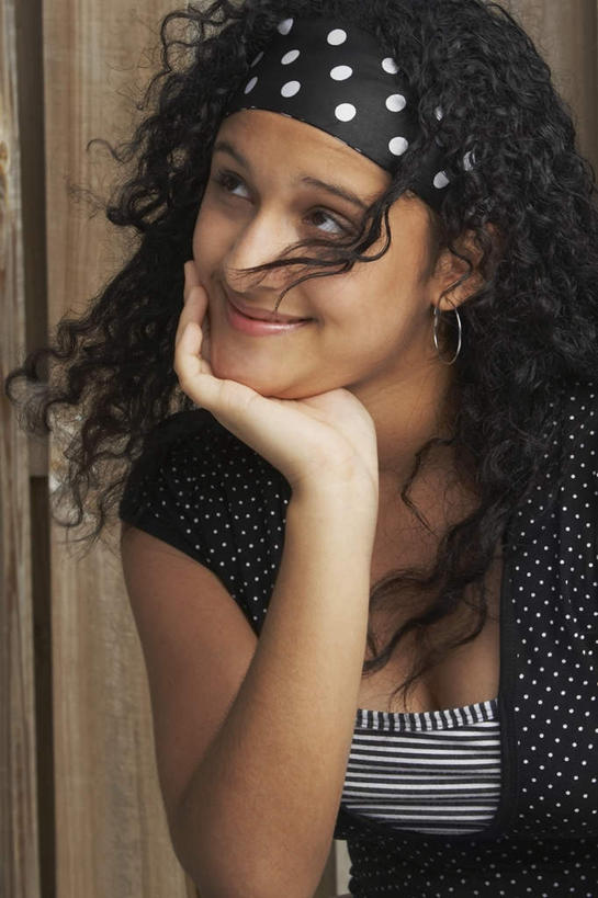 西方人,一个人,坐,笑,微笑,竖图,室外,白天,正面,欧洲,欧洲人,仅一个年轻女性,仅一个女性,仅一个人,撑,圆点,墙,托腮,注视,发带,墙壁,墙面,黑色,看,托,关注,托下巴,年轻女性,女人,女性,白种人,长发,卷发,抬头,仰头,坐着,半身,彩图