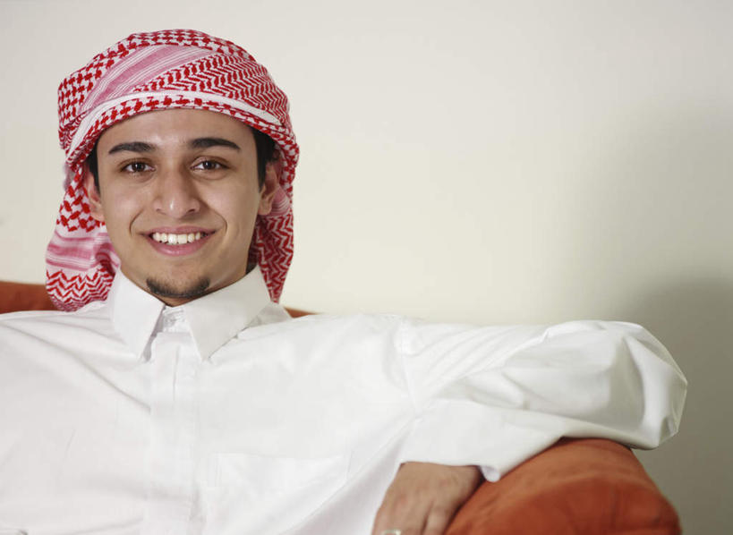 一个人,坐,笑,微笑,露齿笑,横图,室内,白天,正面,民族服装,沙发,亚洲,仅一个男性,仅一个人,阴影,光线,头巾,影子,墙,注视,墙壁,墙面,仅一个年轻男性,观察,看,观看,察看,关注,布艺沙发,男人,男性,年轻男性,阿拉伯人,白种人,亚洲人,坐着,半身,彩图,传统服装,民俗服